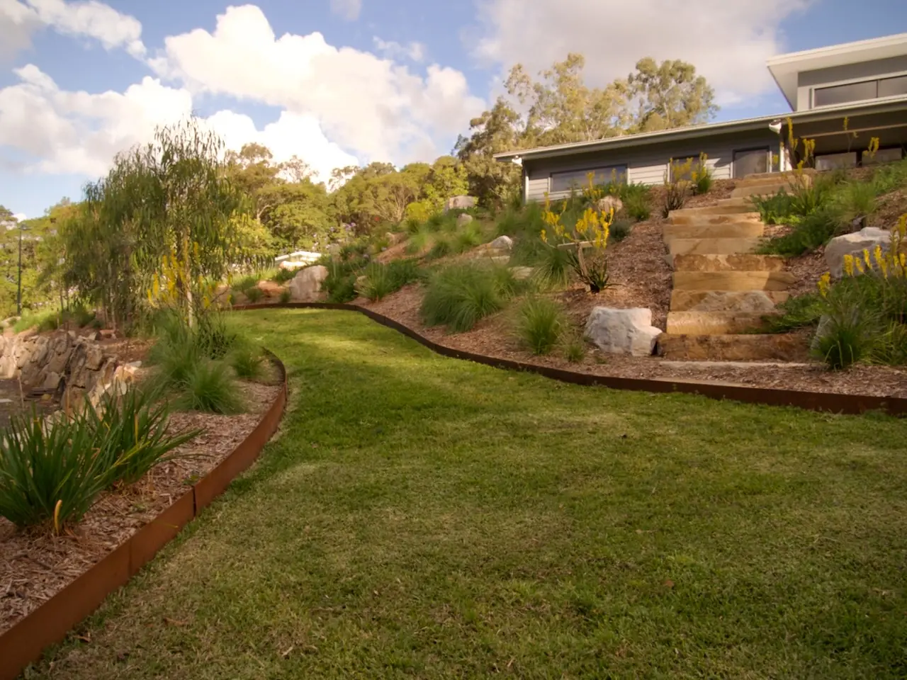 Newly planted garden bed with fresh mulch and sandstone edging