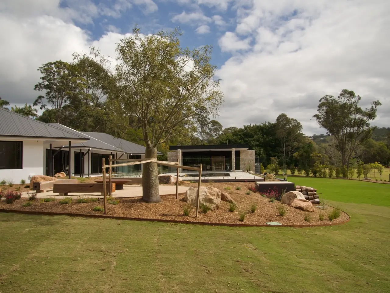 Whole-property view across mown lawn, planted beds and a stone path